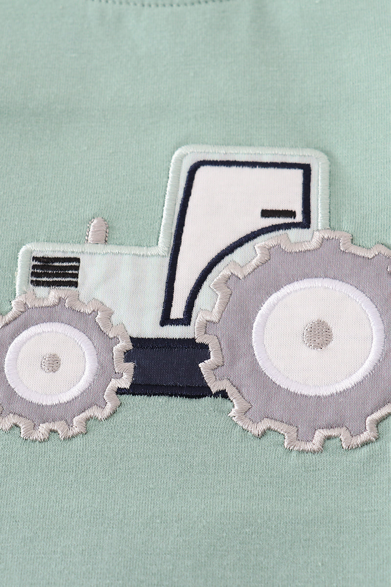 Embroidered tractor design on a light green fabric background