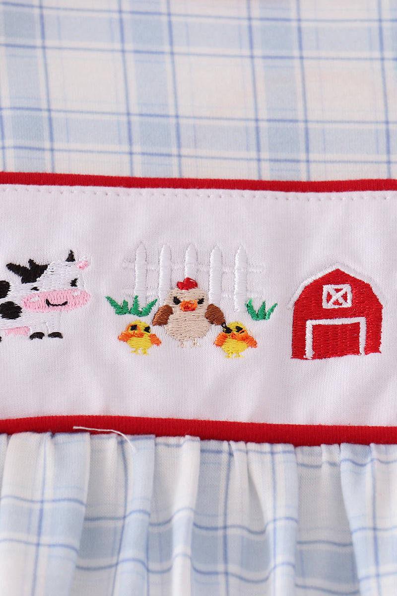Embroidered farm scene on a checkered fabric background