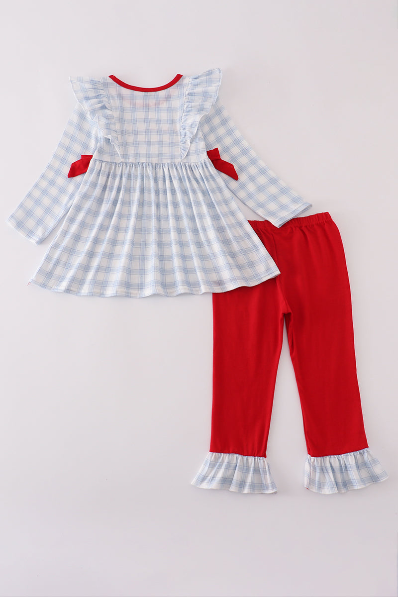 Children's outfit with checkered dress and red pants on a light gray background