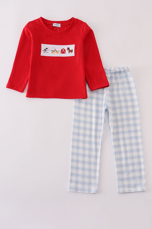 Red long-sleeve shirt with a graphic and blue checkered pants on a light gray background
