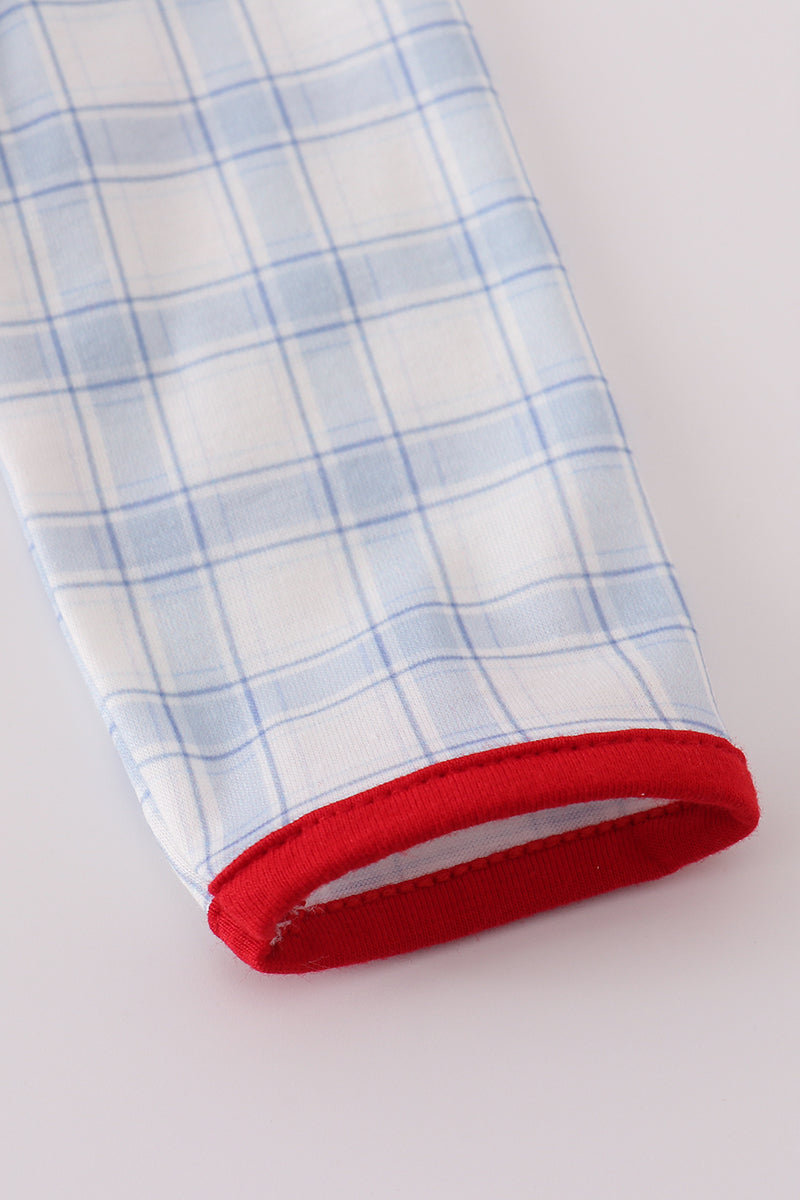 Close-up of a fabric with blue and white check pattern and red trim on a light gray background