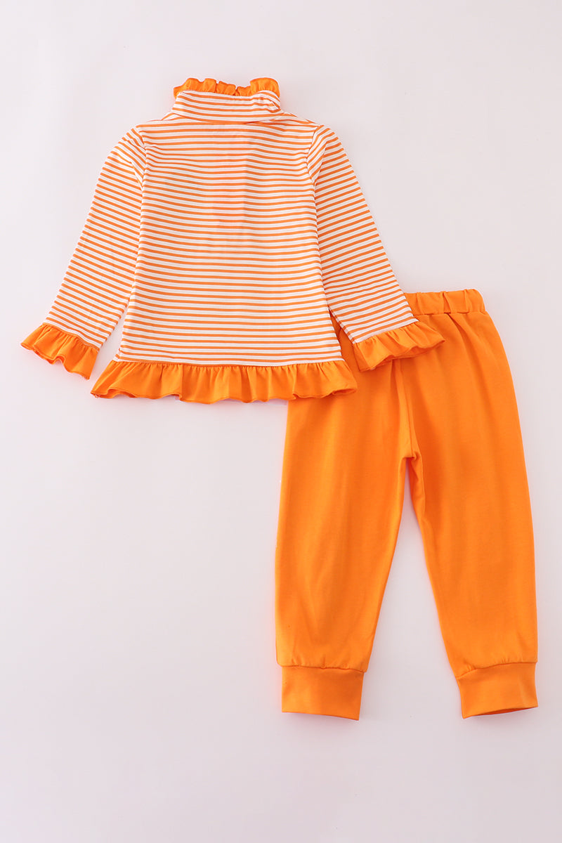 Orange and white striped top with ruffled details and orange pants on a light gray background