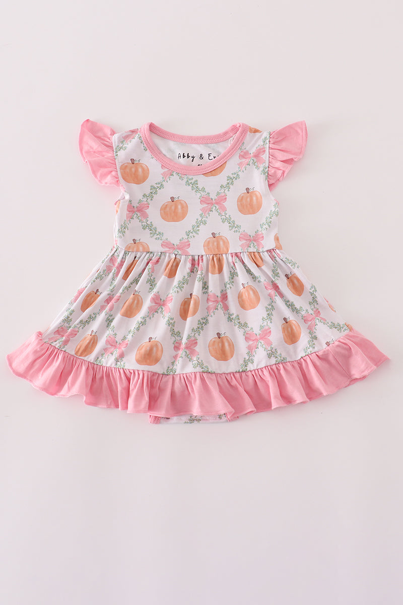 Children's dress with pumpkin pattern and pink ruffles on a light background