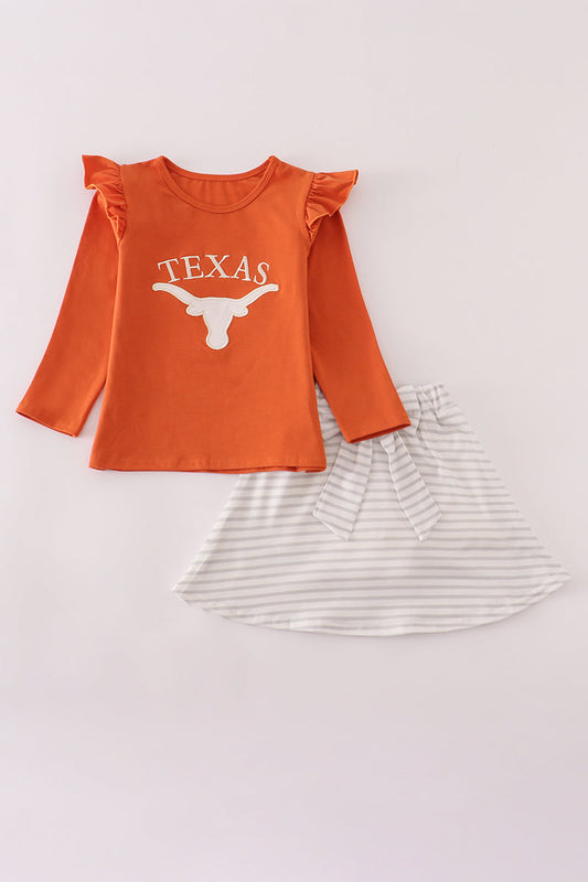 Orange long-sleeve top with 'Texas' and a bull logo, paired with a striped skirt on a light gray background.