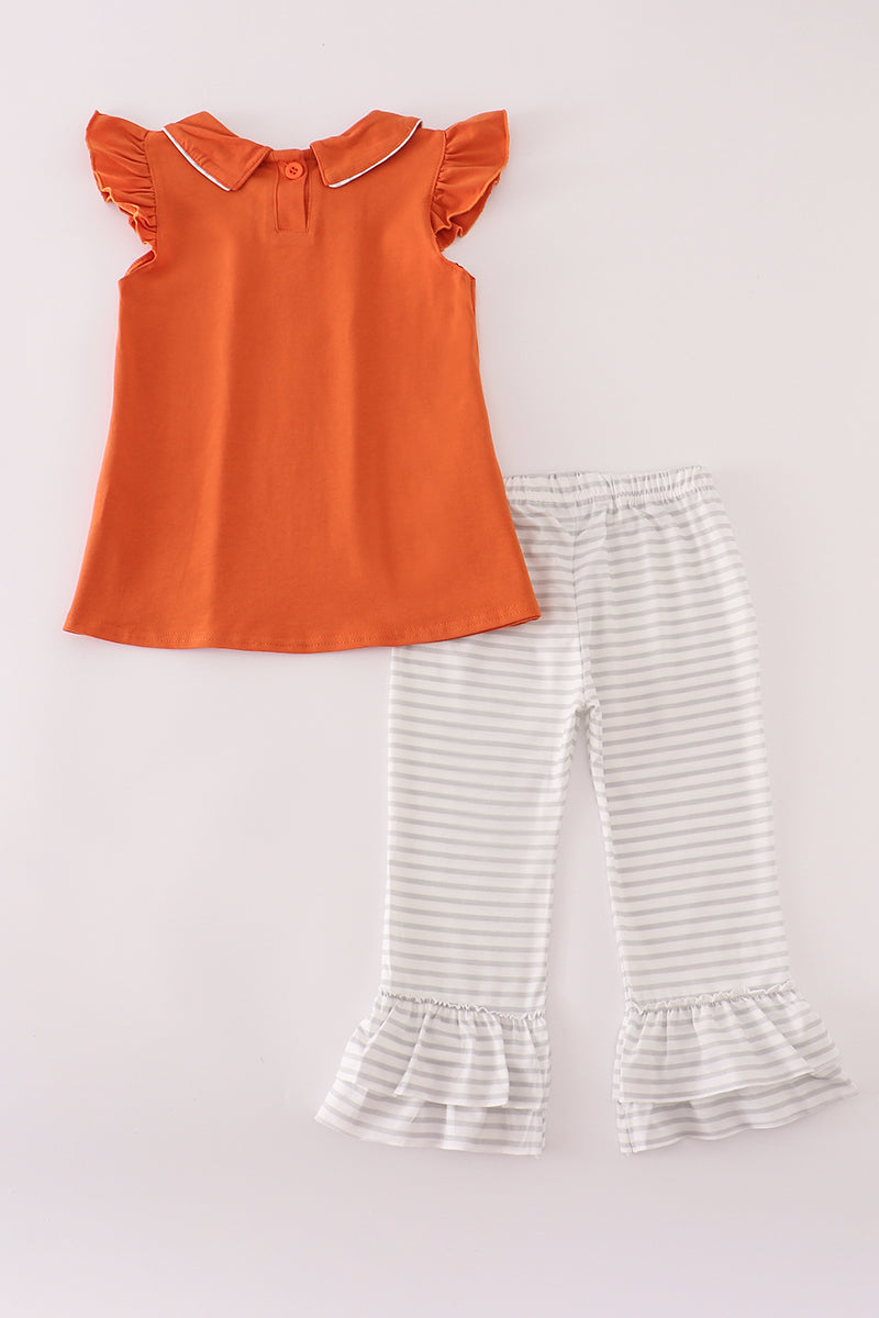 Orange top and striped pants on a light gray background