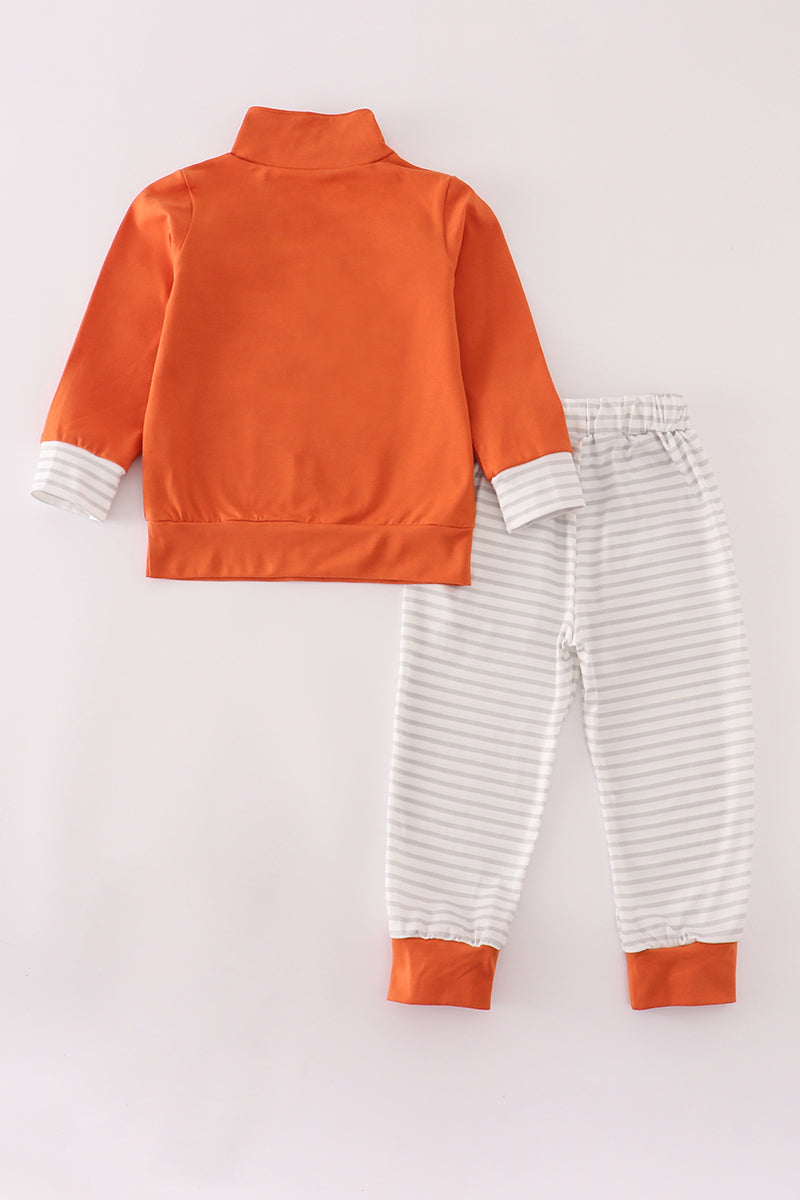 Orange jacket and striped pants on a light gray background