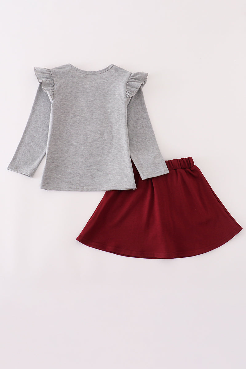 Gray long-sleeve top with ruffled shoulders and a red skirt on a light gray background