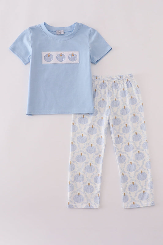 Children's pajama set with blue t-shirt and patterned pants on a light gray background