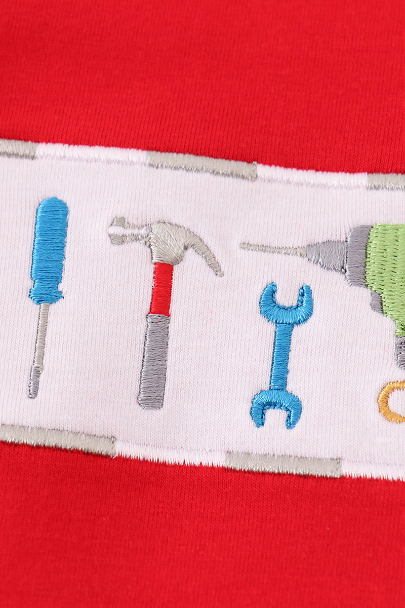 Close-up of a red fabric with white border featuring tool illustrations.