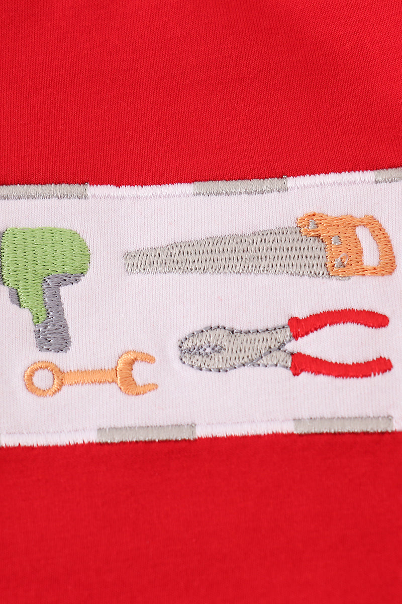 Red shirt with white patch featuring construction tools on a red background