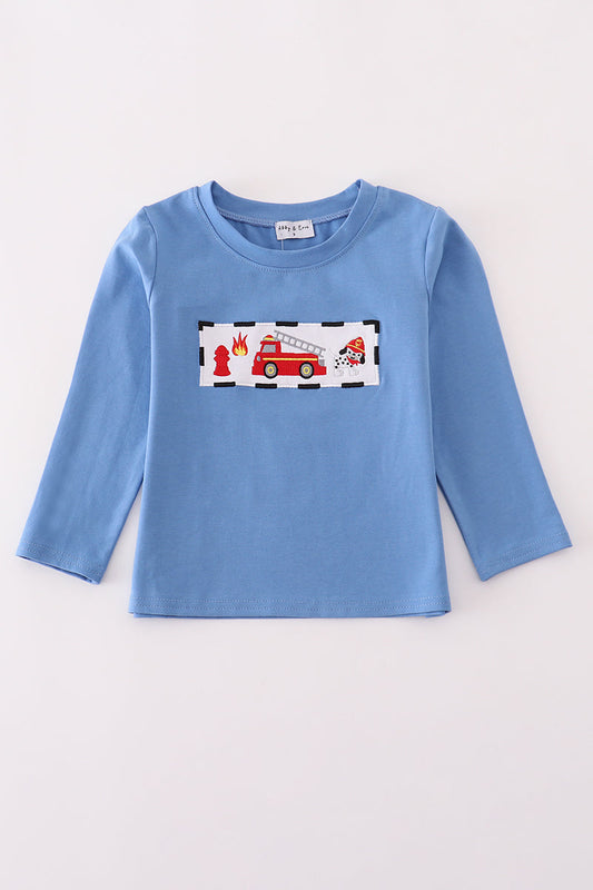 Blue long-sleeve shirt with a fire truck design on a light gray background