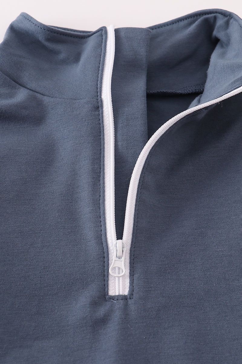 Close-up of a blue garment with a white zipper on a light gray background