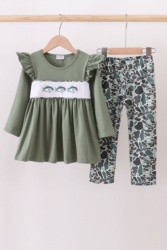 Green dress with ruffled sleeves and patterned leggings on a wooden rack against a white background