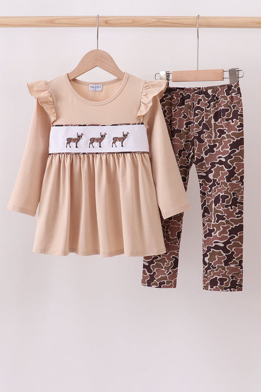 Beige dress with deer pattern and camouflage leggings on a hanger against a white background