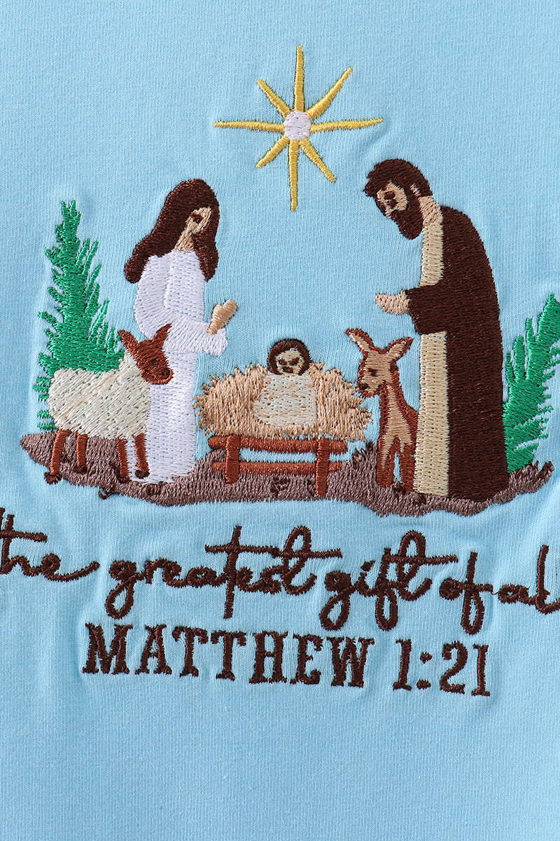 Embroidered nativity scene with text on a light blue background