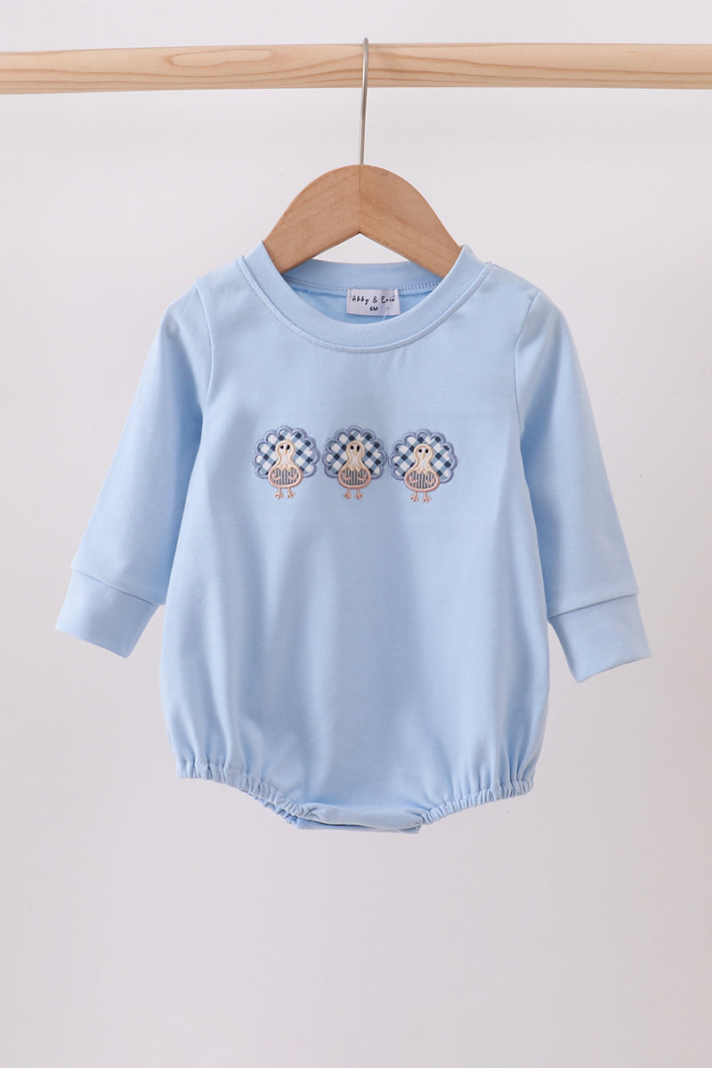 Light blue baby romper with embroidered designs on a wooden hanger against a white background