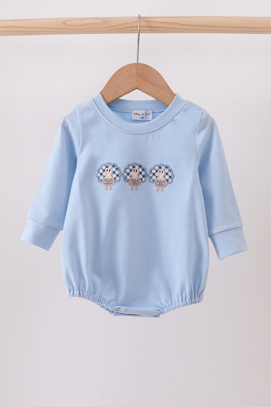 Light blue baby romper with embroidered designs on a wooden hanger against a white background