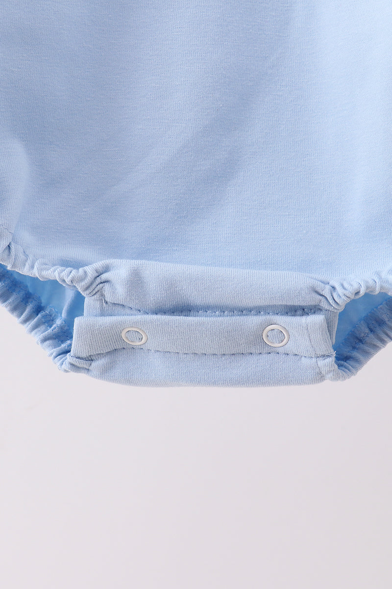 Close-up of a light blue baby romper with button details on a white background