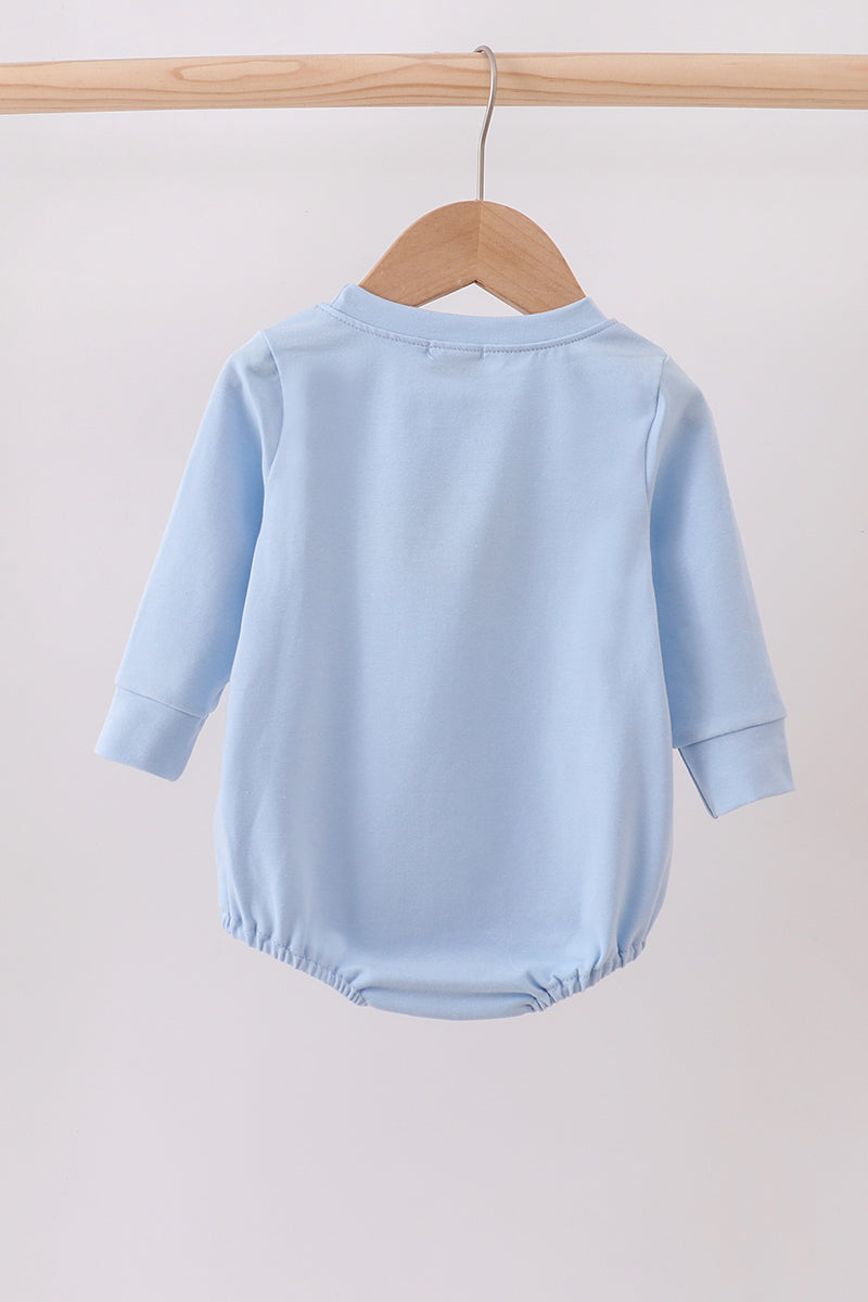 Light blue baby romper on a wooden hanger against a light gray background