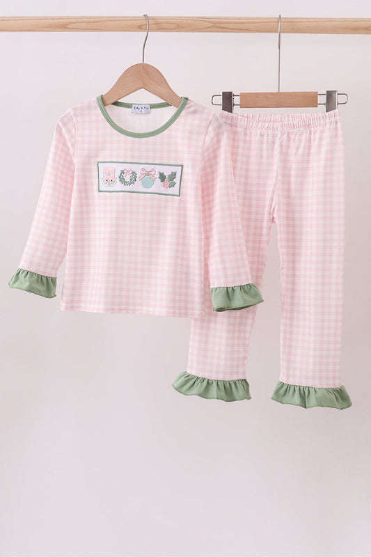 Children's pink and green checkered pajama set on a hanger against a white background