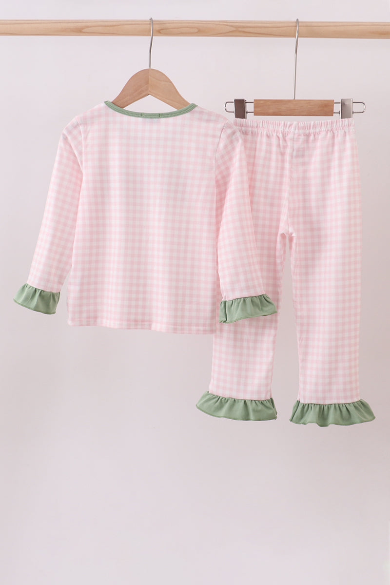 Children's pink checkered pajama set with green trim on a hanger against a white background