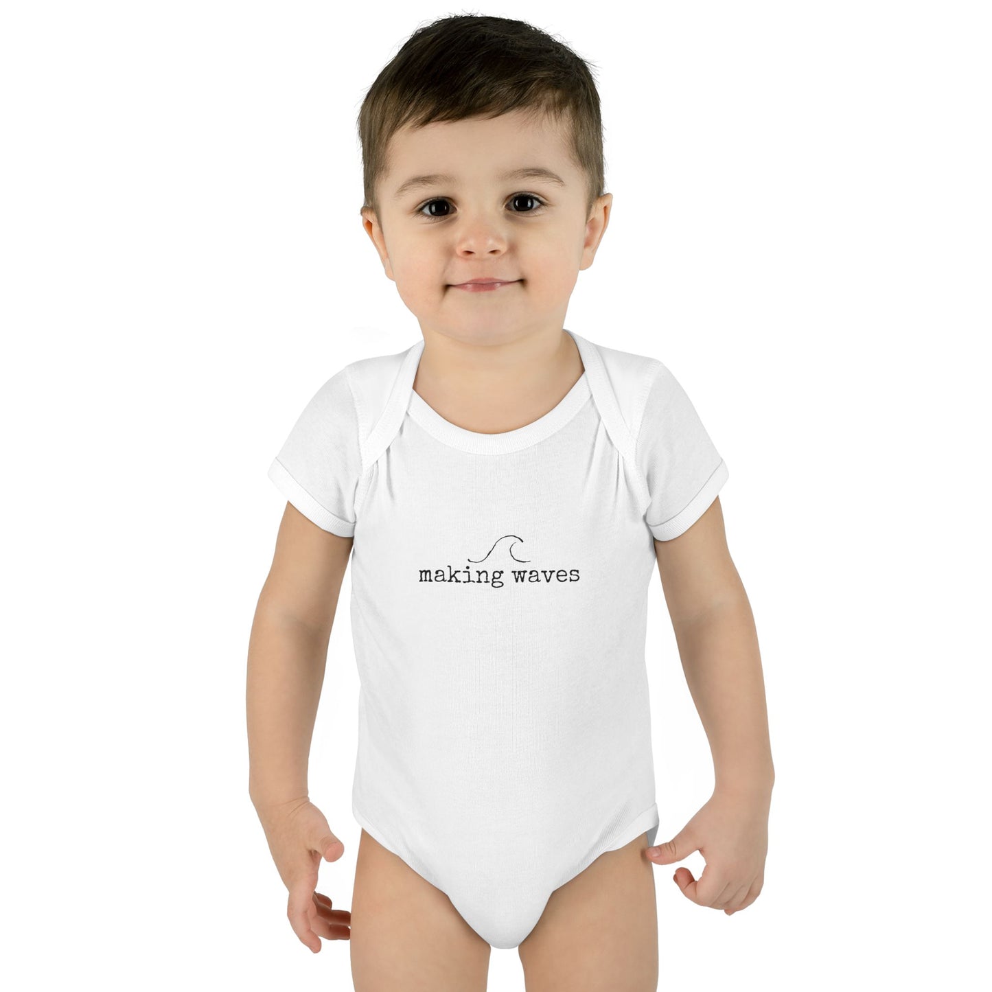 Child wearing a white onesie with 'making waves' text on a white background