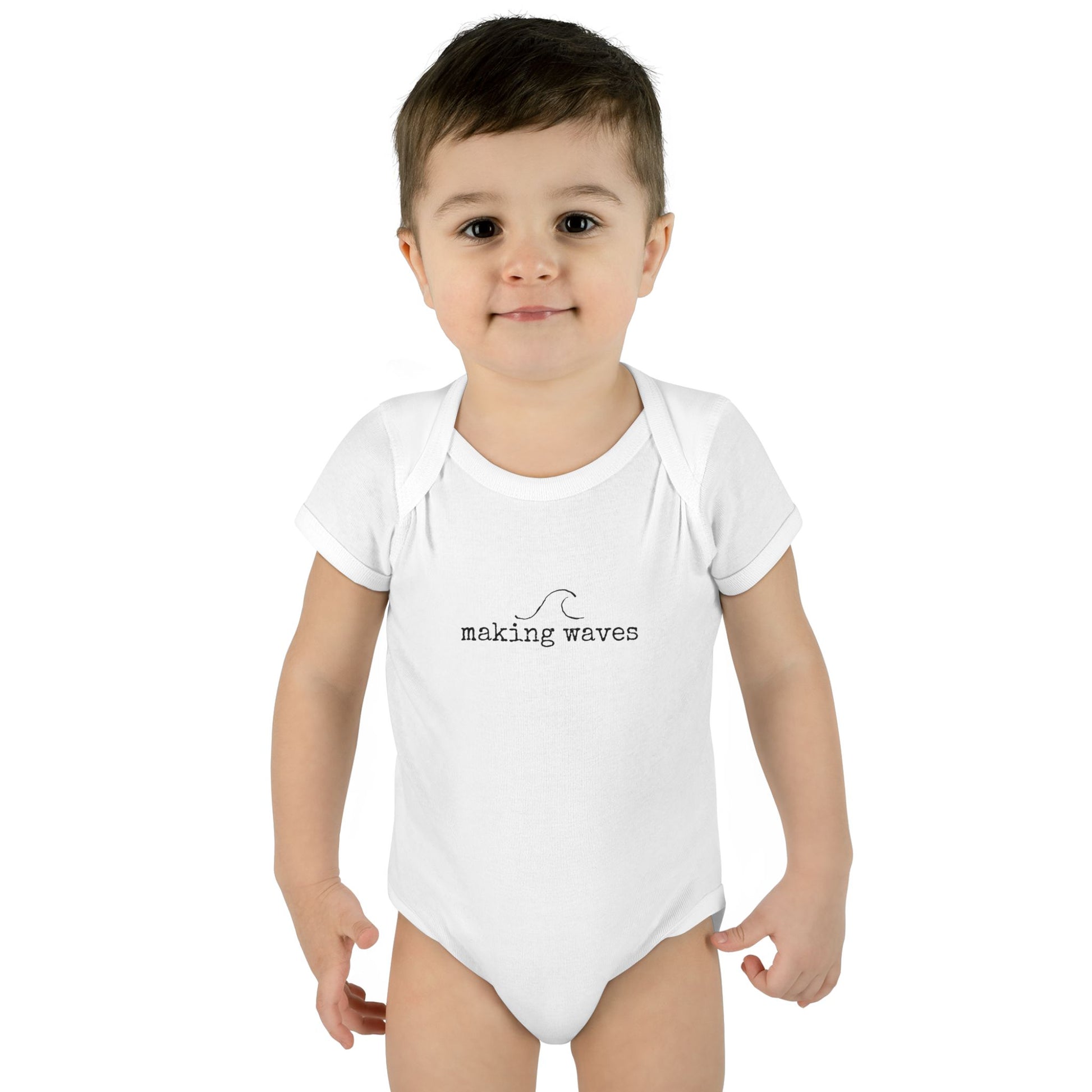 Child wearing a white onesie with 'making waves' text on a white background
