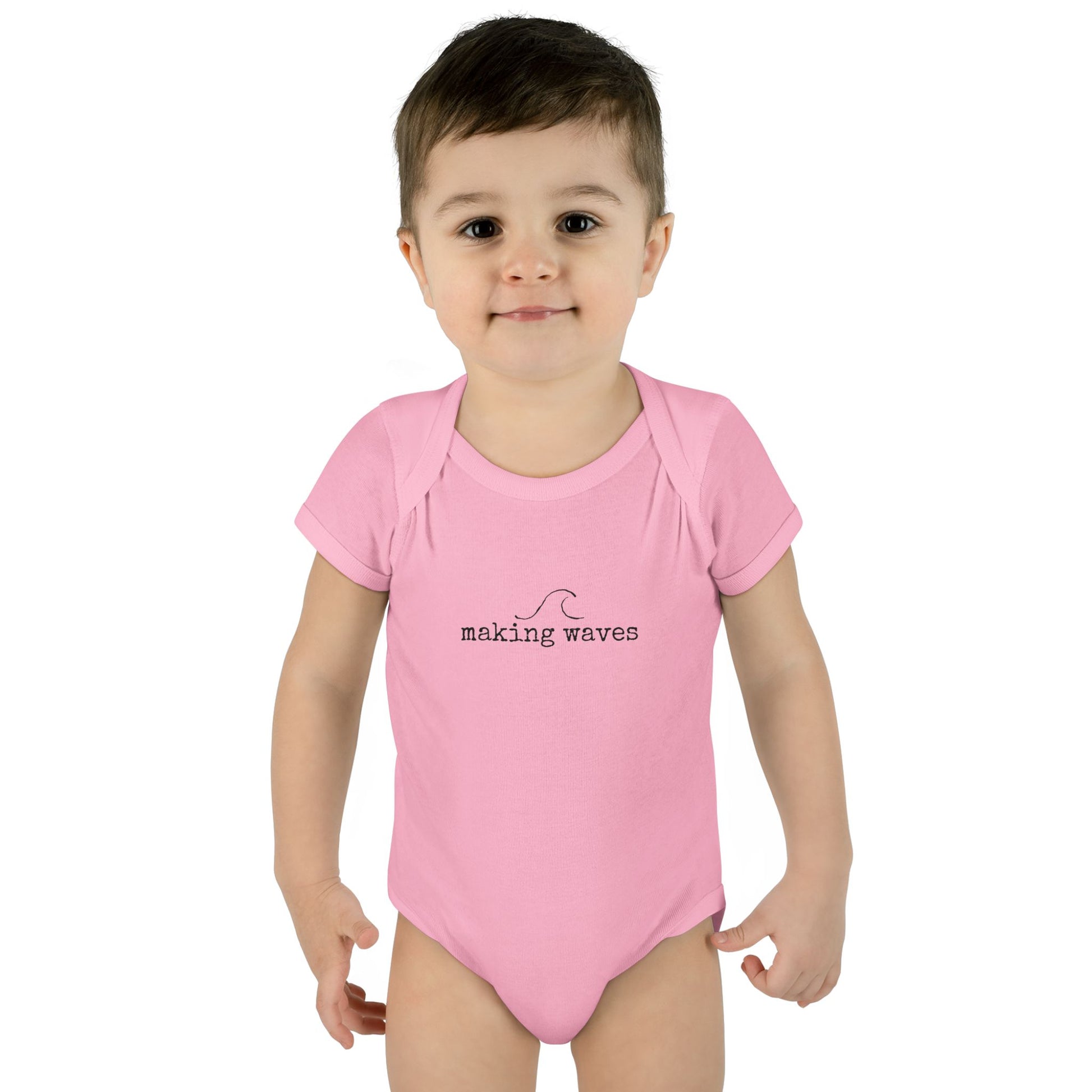 Child wearing a pink 'making waves' onesie on a white background
