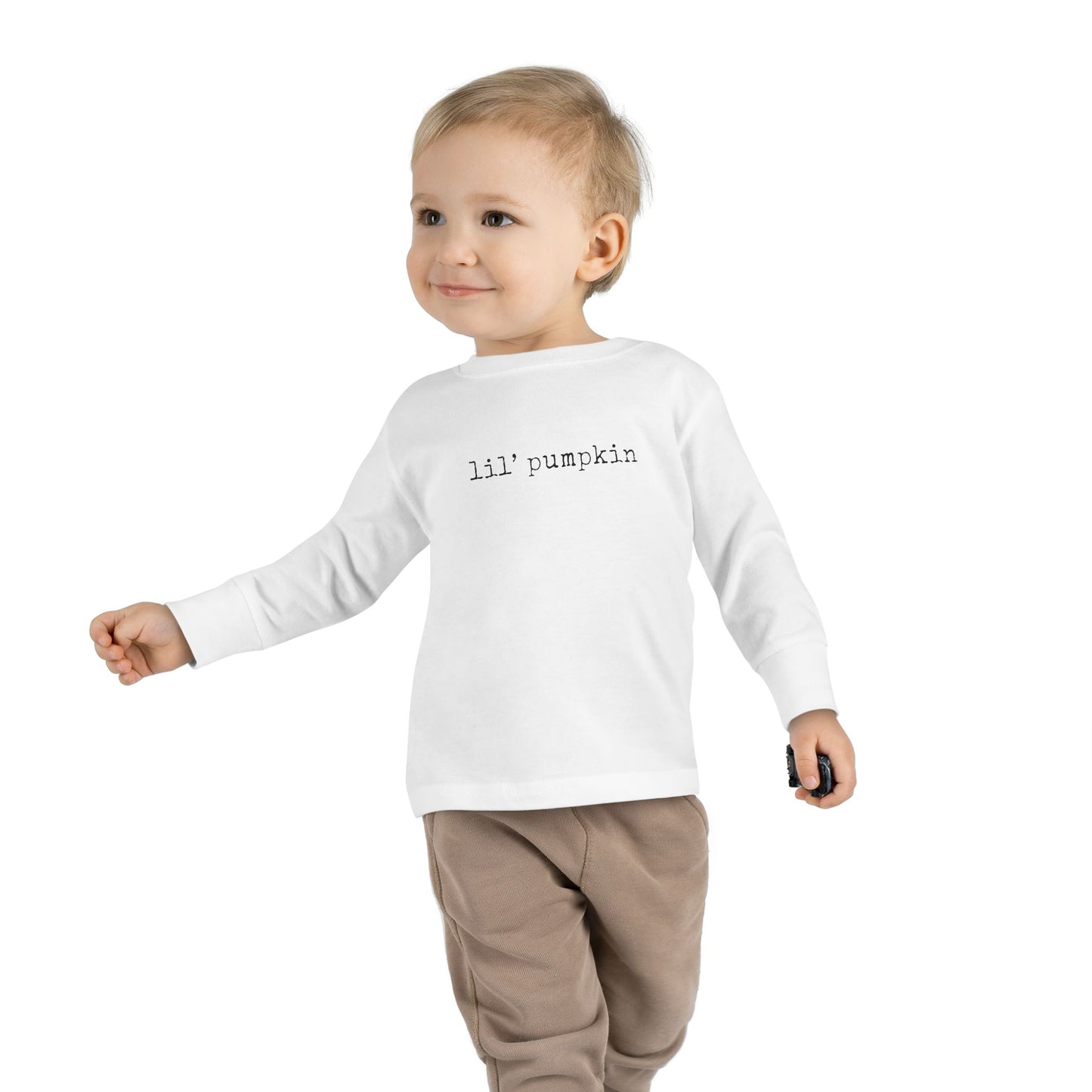 Child wearing a white long-sleeve shirt with 'lil' pumpkin text on a white background
