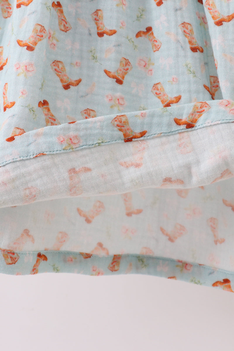 Close-up of a fabric with pink cowgirl boot pattern on a light blue background