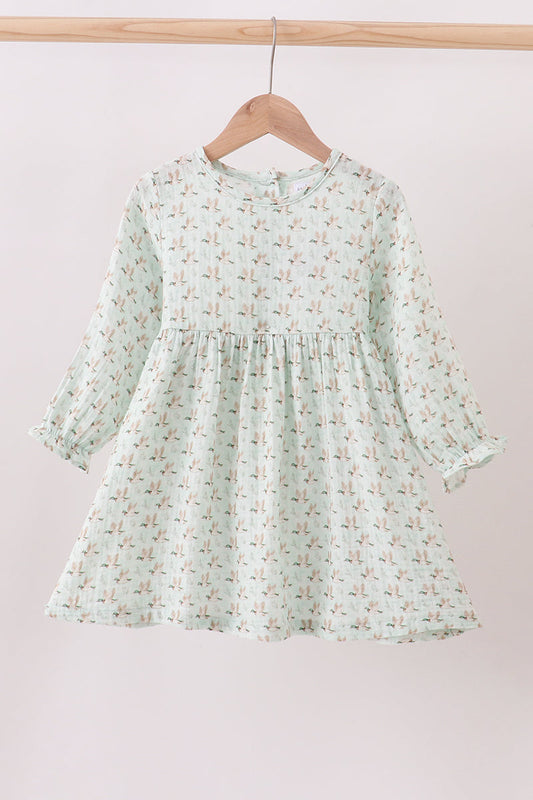 Light green floral dress on a wooden hanger against a light pink background