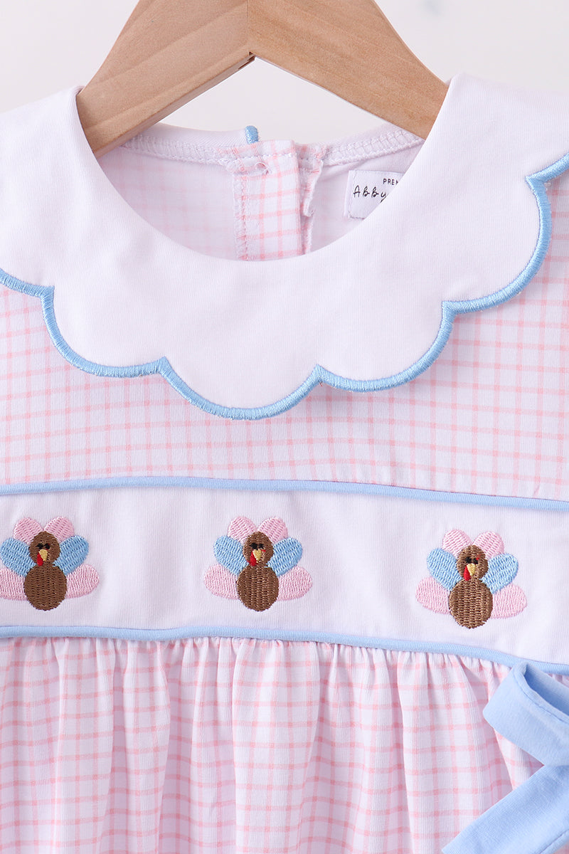 Baby dress with checkered pattern and embroidered designs on a hanger