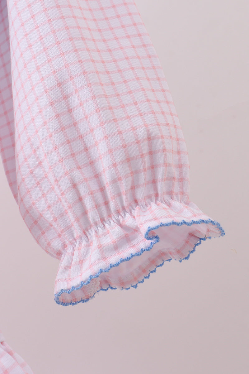 Close-up of a pink and white checkered fabric with blue trim on a beige background