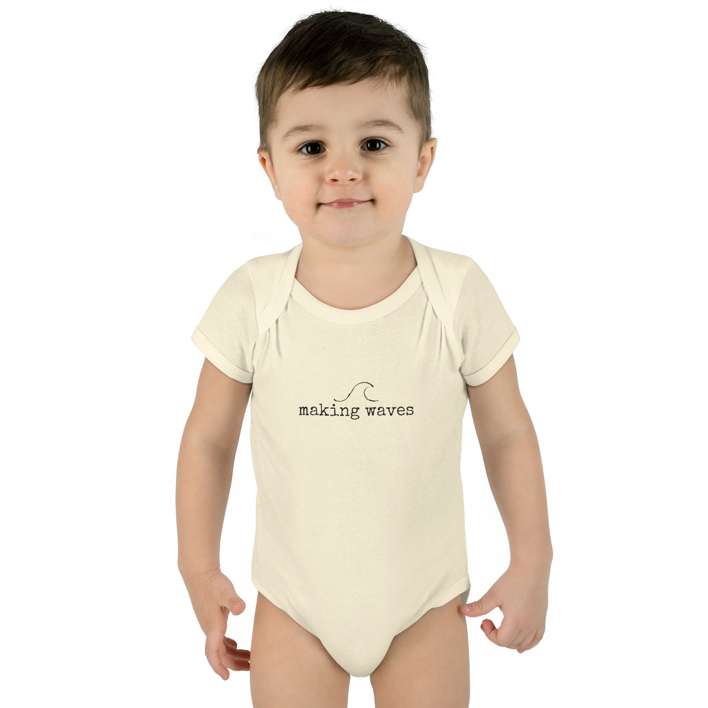Child wearing a white onesie with 'making waves' text on a white background