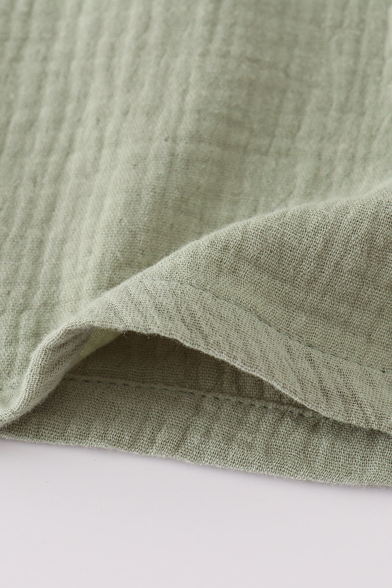 Close-up of green fabric with a textured pattern on a white background