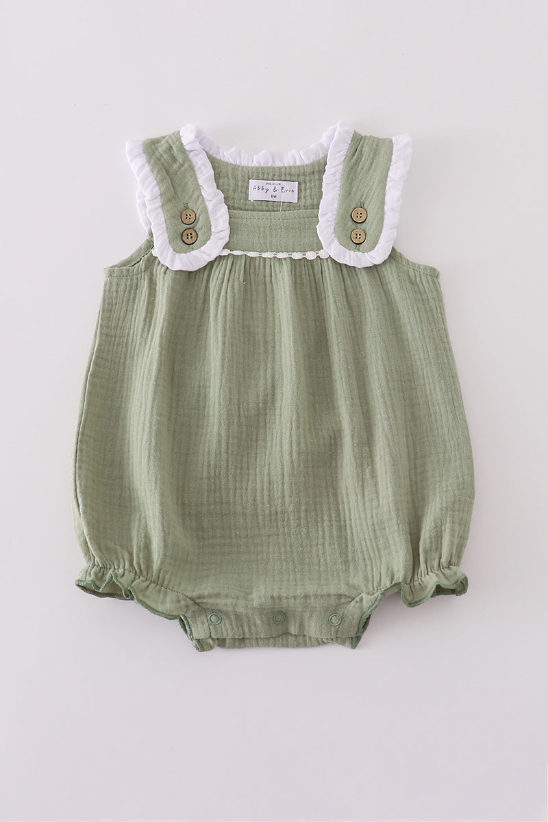 Green baby romper with white lace trim on a light gray background