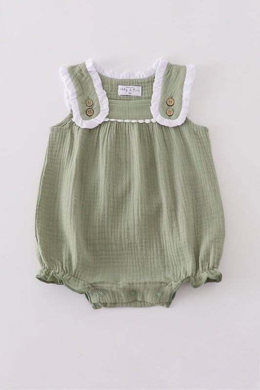 Green baby romper with white lace trim on a light gray background