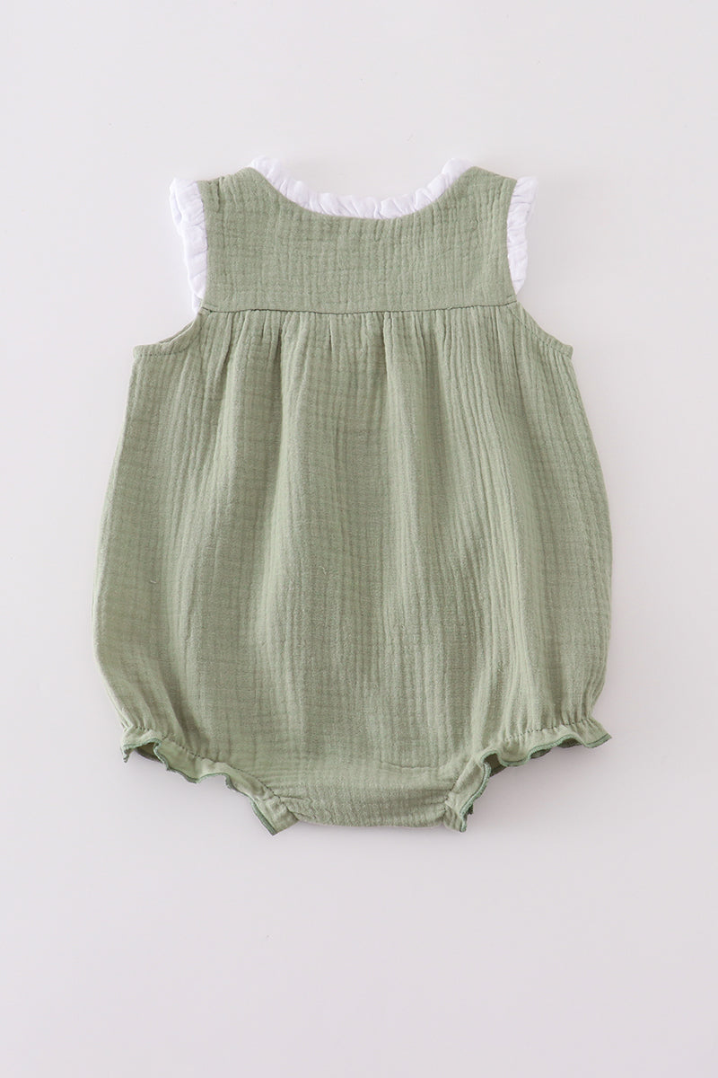 Green baby romper with white lace trim on a light gray background