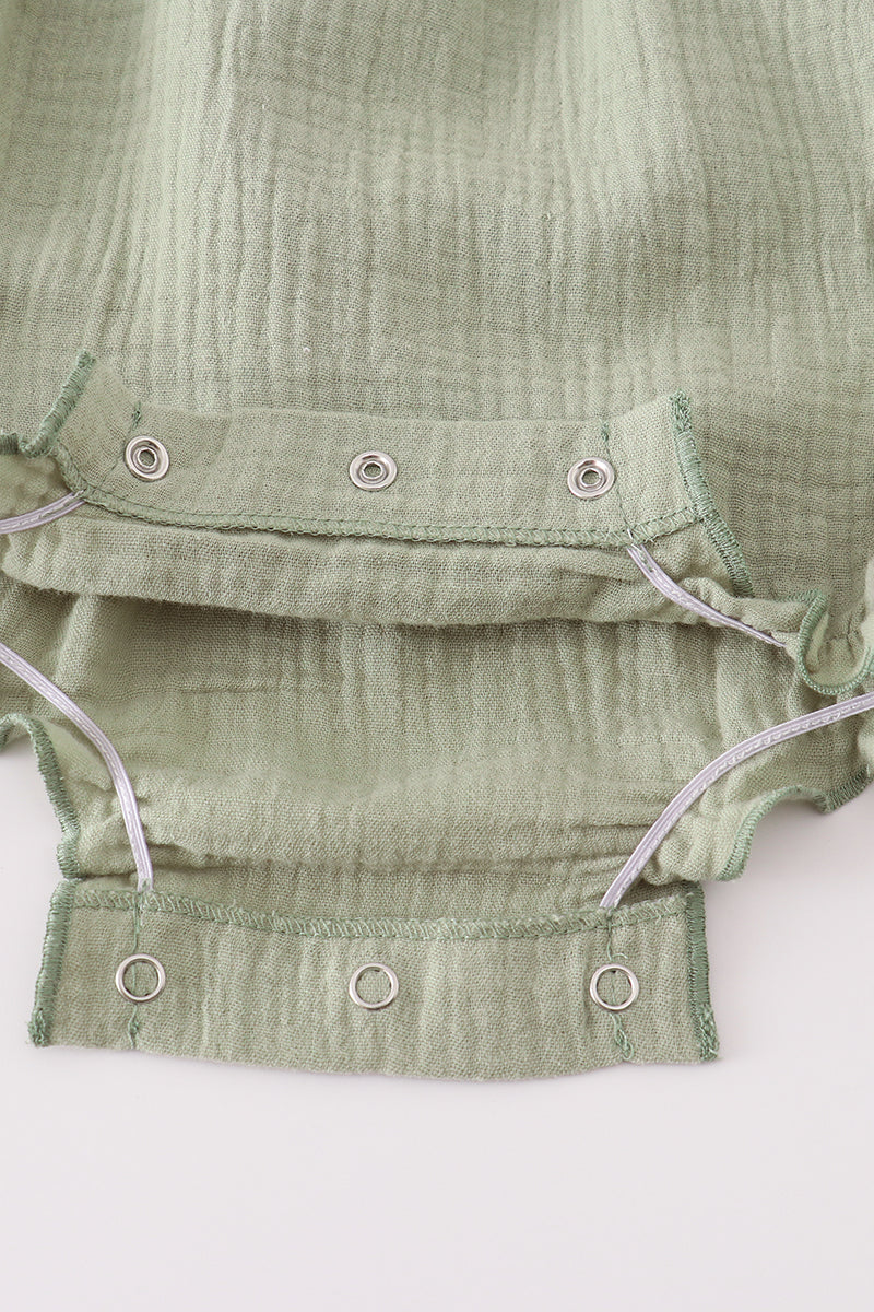 Close-up of a green textured fabric with buttons on a white background
