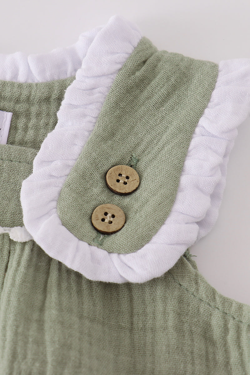 Green baby romper with white collar and wooden buttons on a plain background
