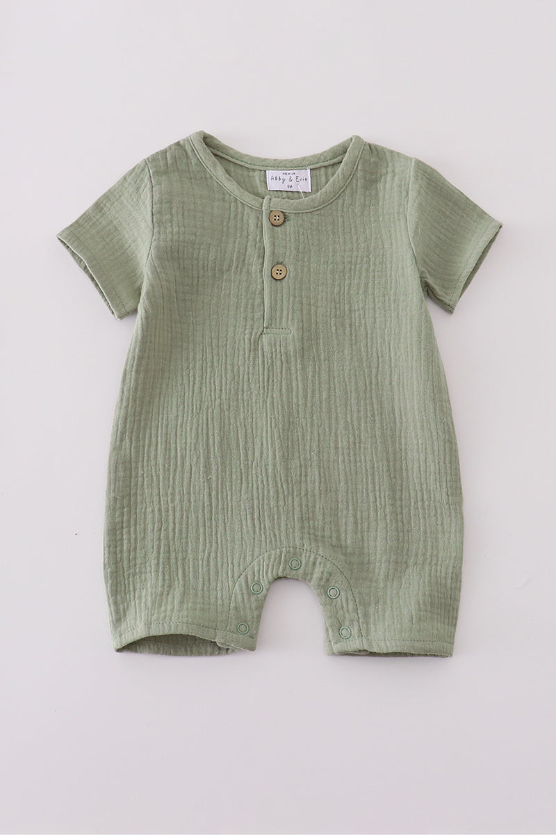 Green baby romper with buttons on a light gray background