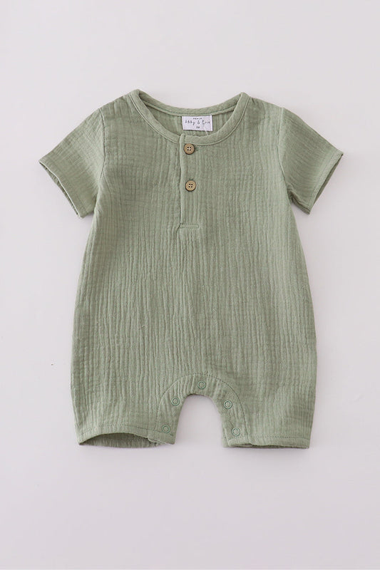 Green baby romper with buttons on a light gray background