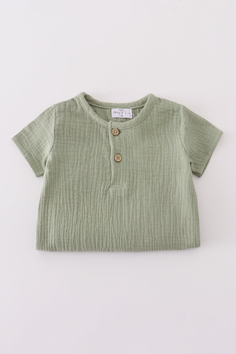 Green baby shirt with buttons on a white background