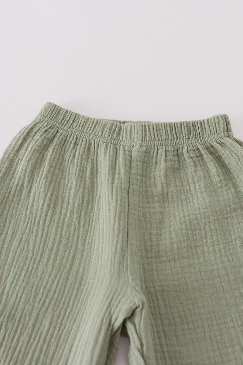 Green ribbed pants on a light gray background