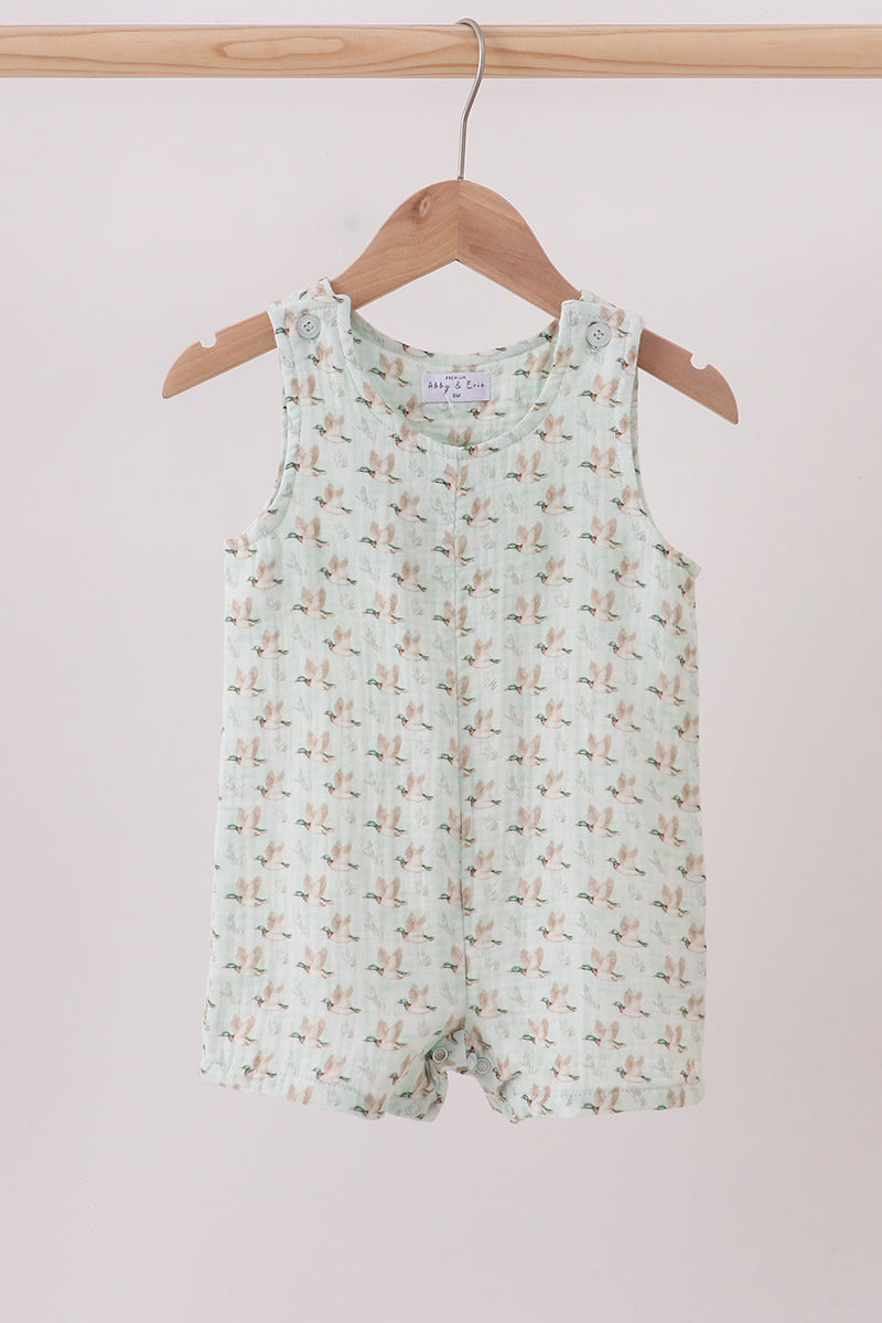 Children's sleeveless romper with floral pattern on a wooden hanger against a light pink background