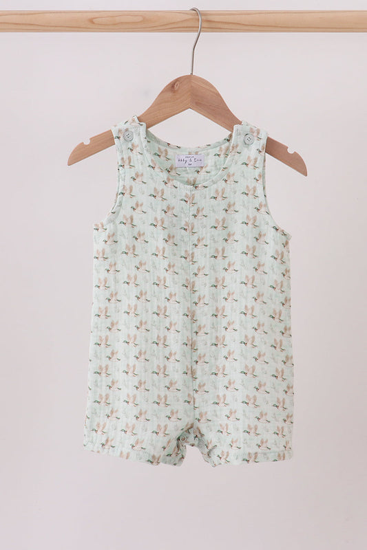 Children's sleeveless romper with floral pattern on a wooden hanger against a light pink background