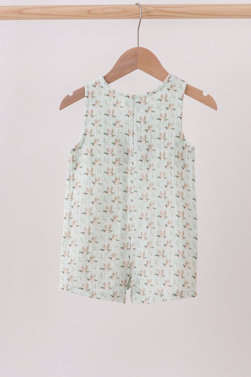 Floral-patterned romper on a wooden hanger against a light pink background