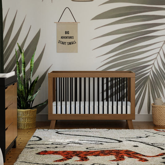 Nursery room with wooden crib, decorative rug, and wall art.