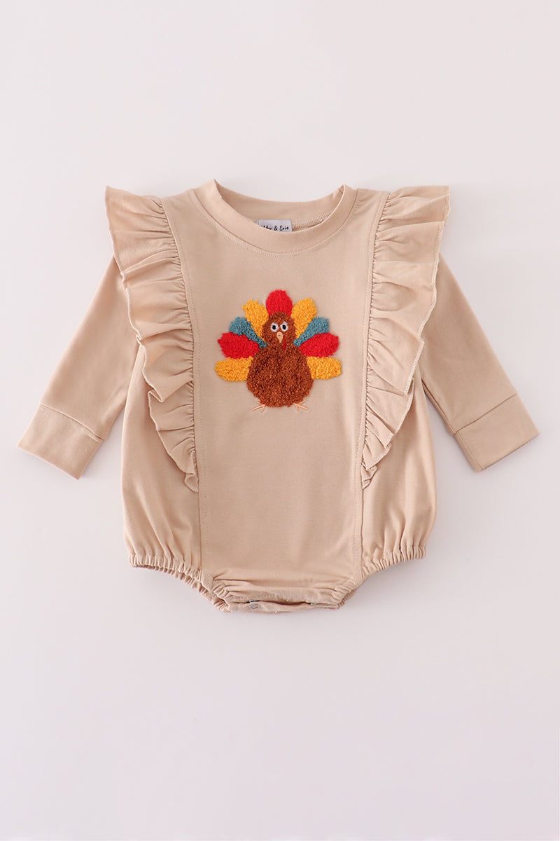 Beige baby romper with a colorful turkey design on a white background