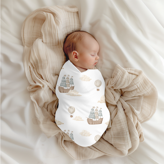 Newborn baby swaddled in a blanket with ship and cloud pattern on a soft beige background